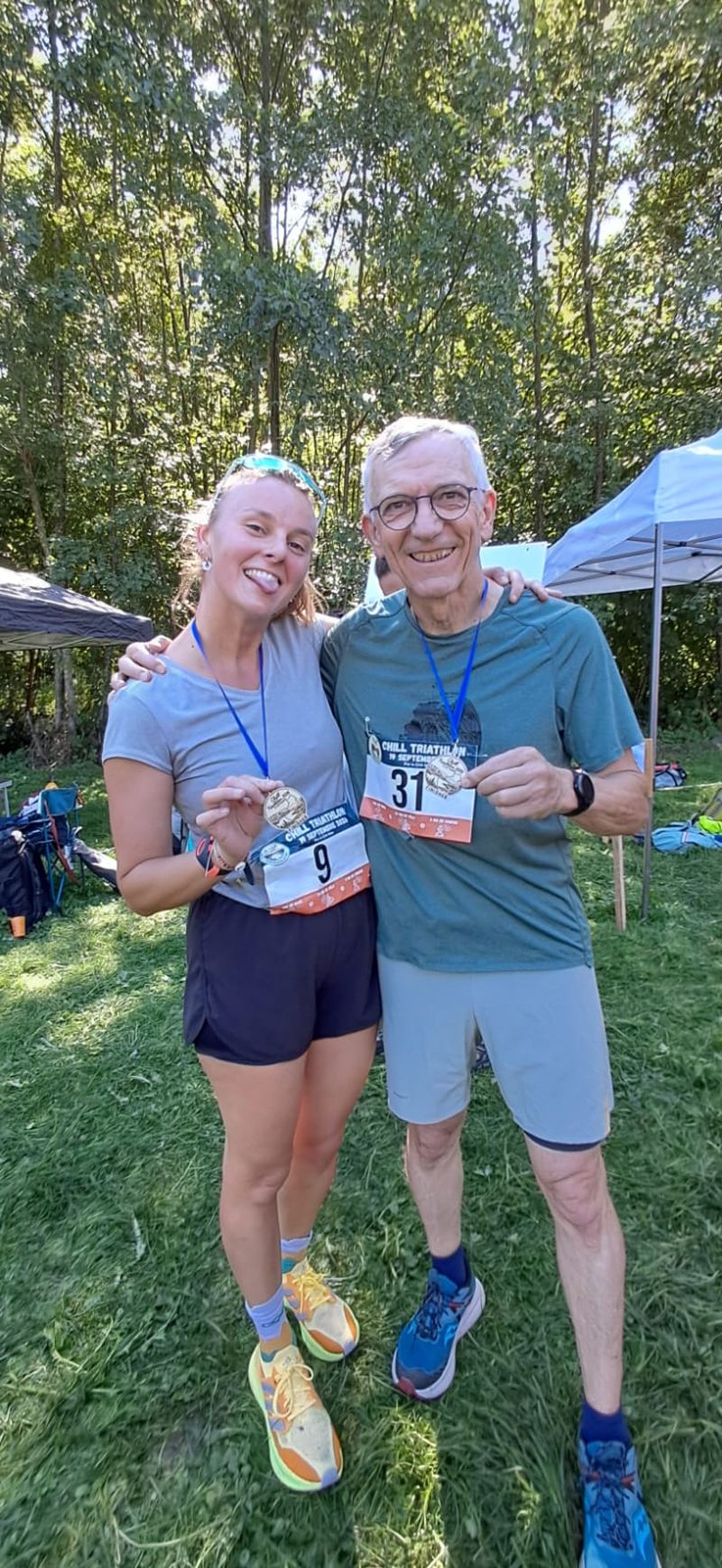 Deux finishers du Chill Triathlon 2026, dossards 9 et 31, montrent leur médaille en bois gravé